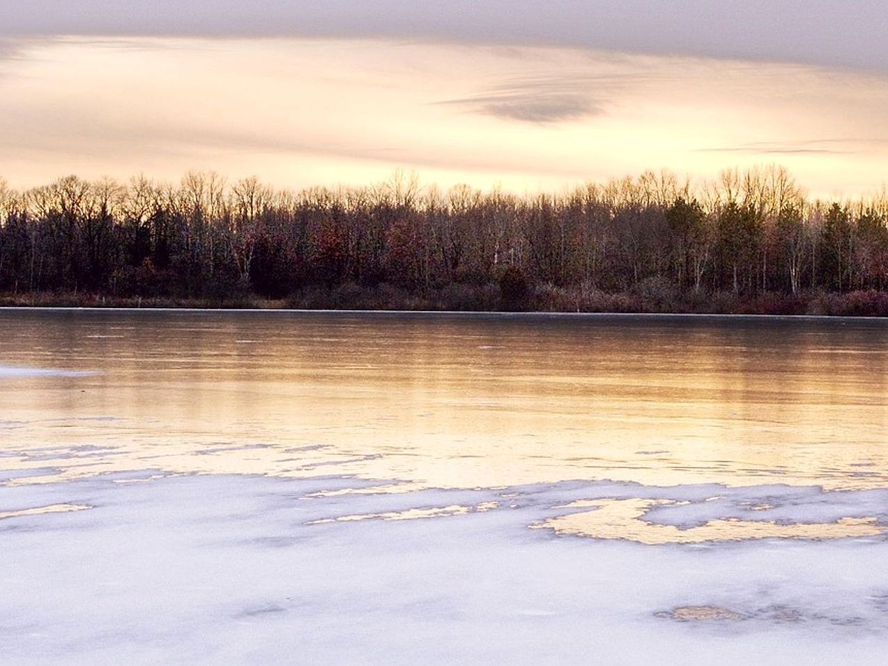 Un lago congelado bajo un cielo que aún no oscurece